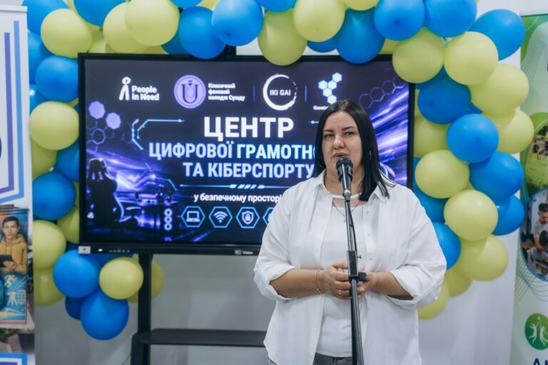Виступ на відкритті Центру цифрової грамотності та кіберспорту в ОКХабі; позаду — екран з назвою центру та логотипами партнерів проєкту.